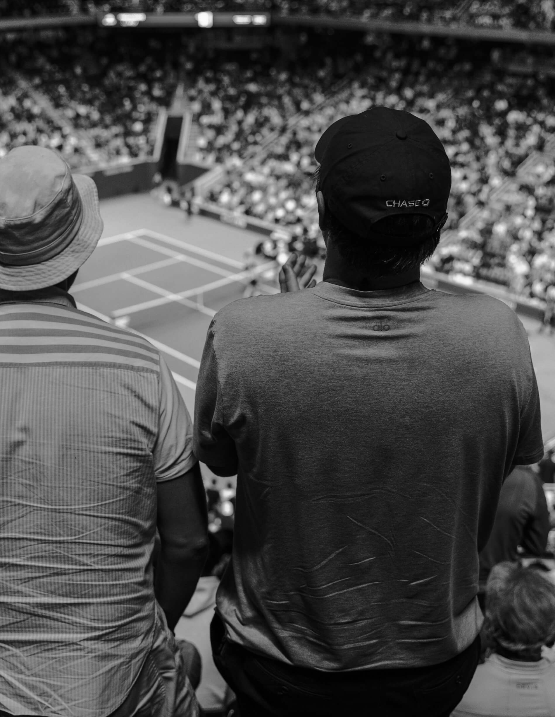 Who We Serve Sports We serve the sports community. The back of two men enjoying the US Open tennis in New York City.
